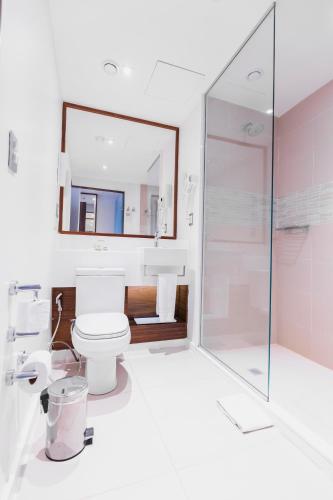 a bathroom with a toilet and a mirror at Bugan Recife Boa Viagem Hotel - by Atlantica in Recife