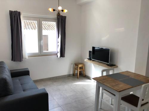 a living room with a couch and a tv and a table at Casa do Viajante - Suite in Zambujeira do Mar