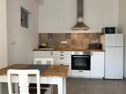 a kitchen with a table and a white refrigerator at Casa do Viajante - Suite in Zambujeira do Mar