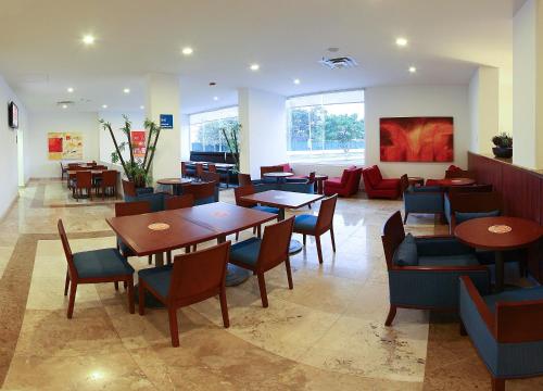 un restaurante con mesas y sillas y un sofá en One Ciudad del Carmen Concordia en Ciudad del Carmen