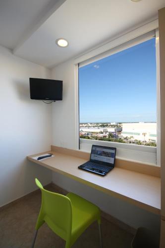 a laptop sitting on a desk in front of a window at One Ciudad del Carmen Concordia in Ciudad del Carmen