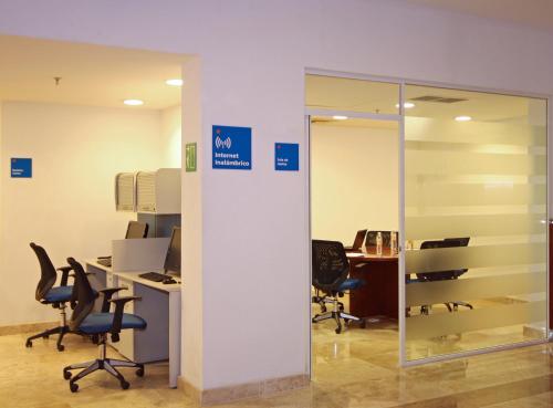 an office with desks and chairs and a glass wall at One Ciudad del Carmen Concordia in Ciudad del Carmen
