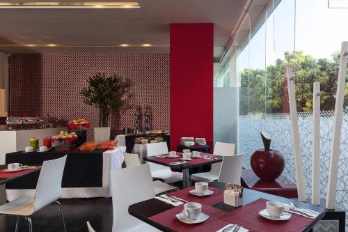 une salle à manger avec des tables et des chaises blanches dans l'établissement Gamma Morelia Belo, à Morelia