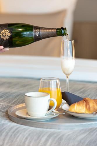 a person pouring a bottle of wine and a glass of orange juice at De Koolputten in Waasmunster