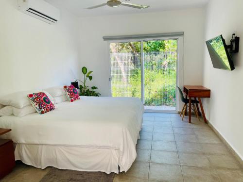 Un dormitorio con una gran cama blanca y una ventana. en Aqua Guesthouse, en Puerto Morelos