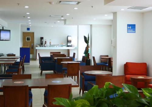 a dining room with tables and blue chairs at One Guadalajara Centro Historico in Guadalajara