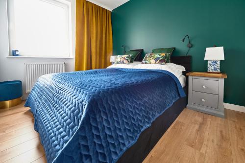 a blue bedroom with a bed with a blue comforter at Apartament Księżycowy in Olsztyn