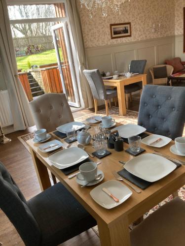 een houten tafel met stoelen en een eetkamer bij Shorelands B&B in Kirkwall