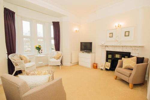 a living room with chairs and a television and a fireplace at EveAnna in Alnwick