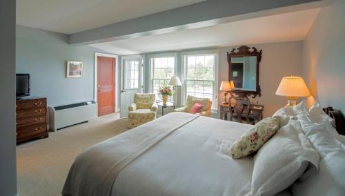 a bedroom with a large white bed and a living room at Black Point Inn in Scarborough