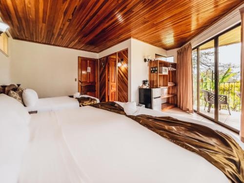 a bedroom with a large bed and a large window at Miradas Arenal Hotel & Hotsprings in Fortuna