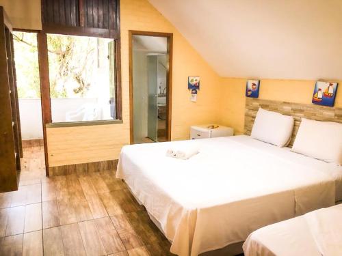 a bedroom with a large white bed and a window at Pousada Solarium-UNIDADE 2 - HOTEL BOUTIQUE in Guarujá