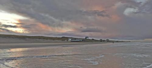a view of a beach with a building in the distance at Hotelhuisje Warmenhuizen #D in Warmenhuizen