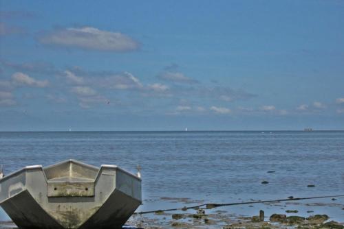 a boat sitting on the shore of the ocean at Hotelhuisje Warmenhuizen #D in Warmenhuizen