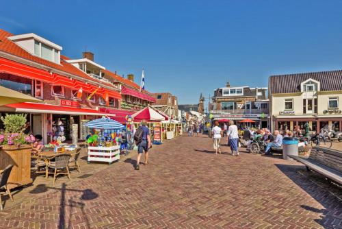 a group of people walking down a street with buildings at Hotelhuisje Warmenhuizen #D in Warmenhuizen