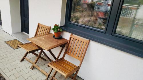 a wooden table and two chairs next to a window at Apartmán Ginko I in Koliba