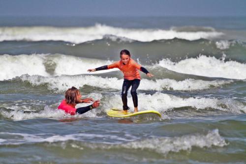 a young child riding a wave on a surfboard in the ocean at Hotelhuisje Warmenhuizen #B in Warmenhuizen