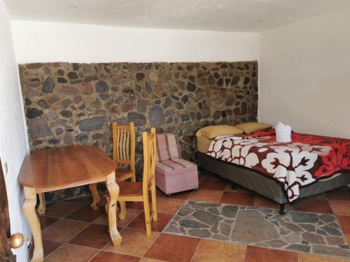 a bedroom with a bed and a table and a chair at Hotel Villa Tzankujil in San Marcos La Laguna