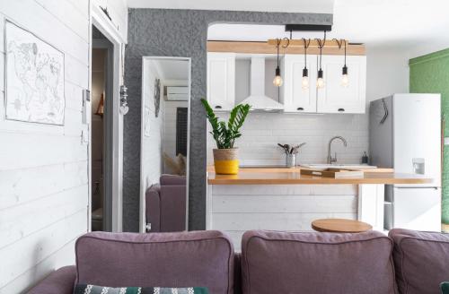 a kitchen and a living room with purple furniture at Appartement Barcares Village VUE MER in Le Barcarès