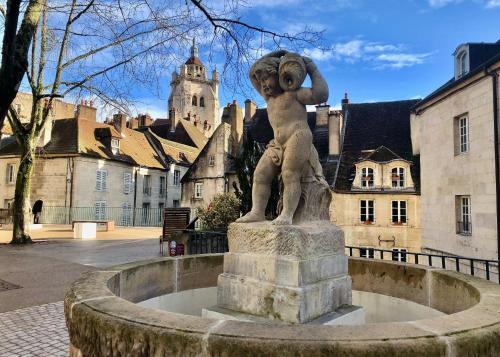 a statue of a girl standing on a fountain in a city at Nos studios au centre ville à Dole in Dole