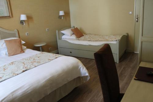 a hotel room with two beds and a table at Hôtel Restaurant Le Moulin de Saint Verand in Saint-Vérand