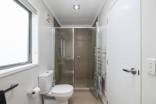 a bathroom with a toilet and a shower at Modern Marine Parade Apartment in Mount Maunganui