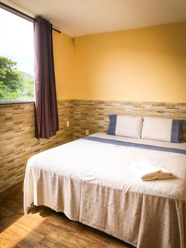a bedroom with a large white bed with a window at Pousada Solarium UNIDADE 1 ECONOMICA-BÁSICA in Guarujá