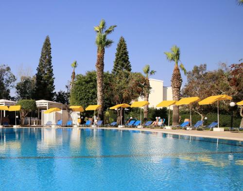 a large swimming pool with chairs and umbrellas at Papouis Protaras Hotel in Protaras