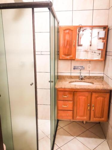 a bathroom with a sink and a glass shower at Pousada Solarium UNIDADE 1 ECONOMICA-BÁSICA in Guarujá