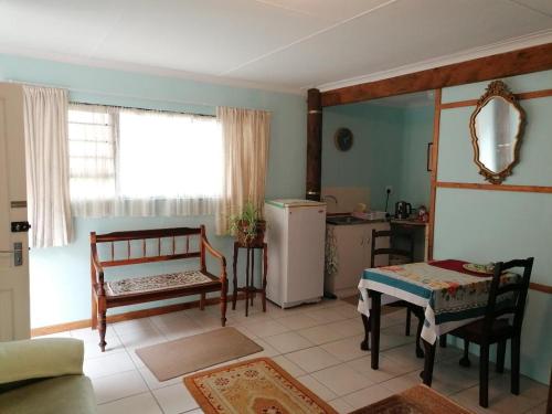 ein Wohnzimmer mit einem Kühlschrank, einem Tisch und Stühlen in der Unterkunft Sea & Lakes self-catering in Wilderness