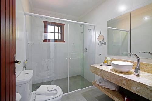 a bathroom with a shower and a toilet and a sink at Casablanca Hotel Boutique in Campos do Jordão