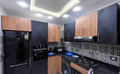 a kitchen with black appliances and wooden cabinets at New Apartment AlMohandessin near Shehab street in Cairo