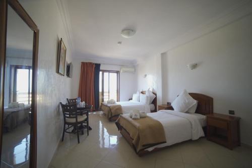 サフィにあるHôtel Riad Asfiのベッド2台とテーブルが備わるホテルルームです。