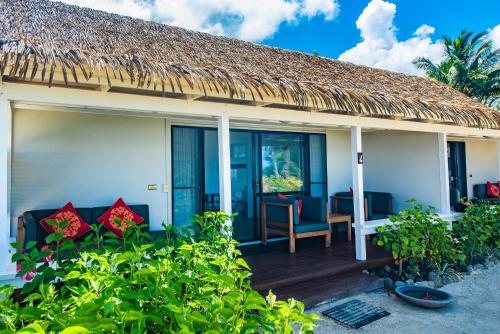 a cottage with a deck with chairs and a table at Manuia Beach Resort in Rarotonga