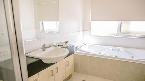 a bathroom with a sink and a bath tub at McMillans of Metung Coastal Resort in Metung