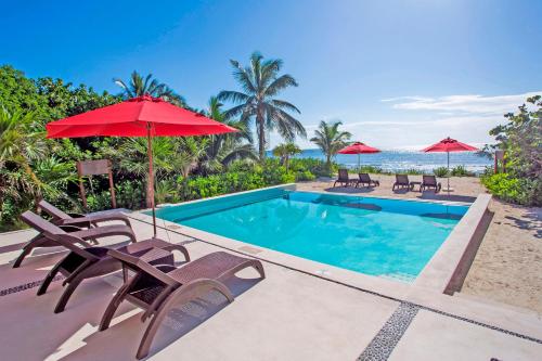 a swimming pool with chairs and umbrellas and the ocean at Tao Ocean Luxury Home Akumal in Akumal