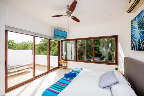 a bedroom with a bed and large windows at Tao Ocean Luxury Home Akumal in Akumal