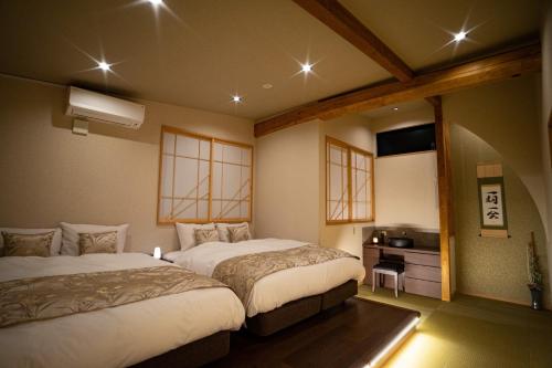 a bedroom with two beds and a television in it at Ixyz別邸 月夜見の宿 in Nagoya