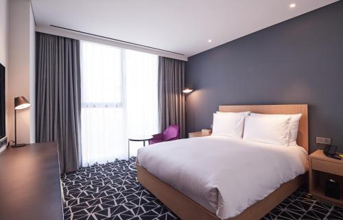a hotel room with a bed and a large window at L7 GANGNAM by LOTTE in Seoul