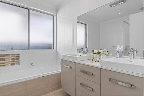 a white bathroom with two sinks and a tub at Pelican House, 5 Bedroom house, Pool in Chittaway Point