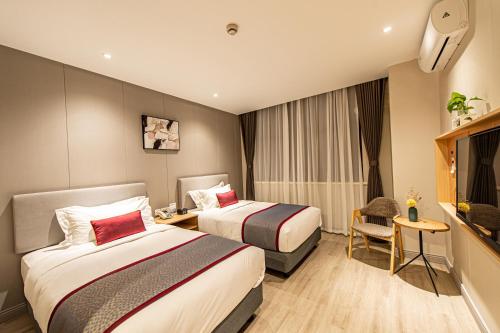 a hotel room with two beds and a television at Shanghai JOYFUL YARD Hotel-Free shuttle bus to Pudong Airport and Disneyland in Shanghai