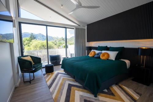 ein Schlafzimmer mit einem grünen Bett und einem großen Fenster in der Unterkunft Dacha on Maggie No#1 OPULENT AND LUXURIOUS in Nelly Bay