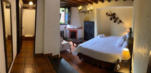 a bedroom with a bed and a room with a fireplace at Hotel Posada San Pedro in Antigua Guatemala
