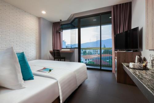 a hotel room with a bed and a television at Cross Vibe Chiang Mai Decem, Nimman in Chiang Mai