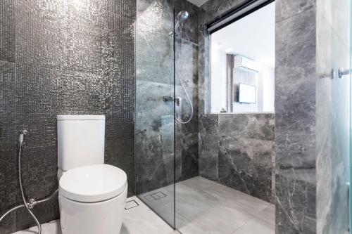 a bathroom with a toilet and a glass shower at Cross Vibe Chiang Mai Decem, Nimman in Chiang Mai
