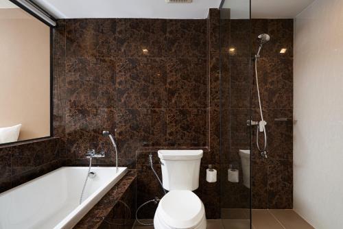 a bathroom with a toilet and a shower and a tub at Cross Vibe Chiang Mai Decem, Nimman in Chiang Mai
