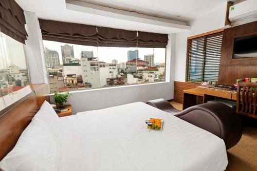 sypialnia z białym łóżkiem i dużym oknem w obiekcie Night Hotel w mieście Hanoi