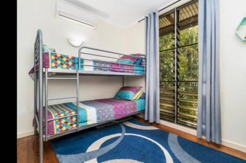 a room with bunk beds and a window at Elevated Tropical House in Casuarina