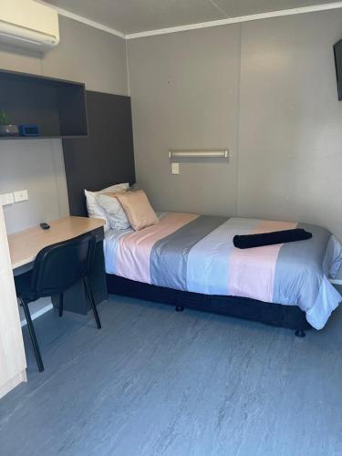 Mały pokój z łóżkiem, biurkiem i biurkiem w obiekcie Adventureland Cabins w mieście Darawank