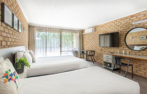 Habitación de hotel con 2 camas y escritorio en Sunshine Coast Motor Lodge, en Woombye